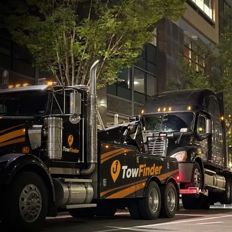 TowFinder heavy duty wrecker towing a semi truck at night in Detroit