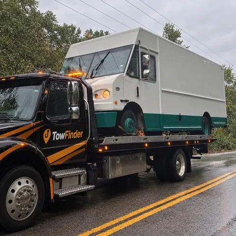TowFinder flatbed tow truck carrying a white step van in Metro Detroit