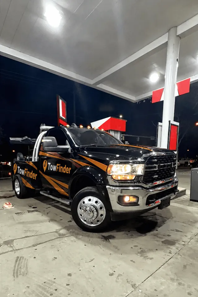 Black TowFinder wrecker tow truck with amber graphics at a gas station at night in Metro Detroit