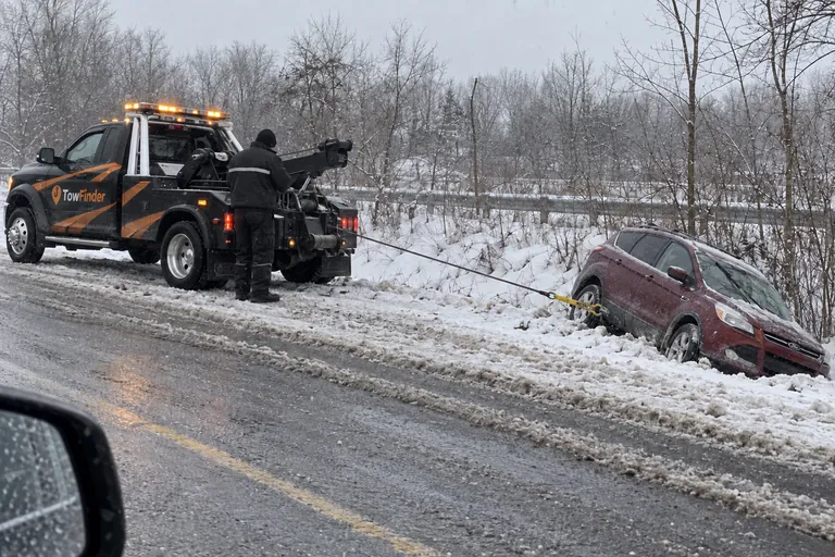 TowFinder wrecker winching an SUV out of a snowy ditch near Detroit